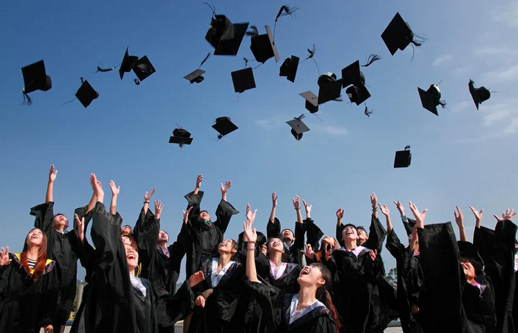 A group of graduates joyfully toss their caps into the air, celebrating their academic achievements together.